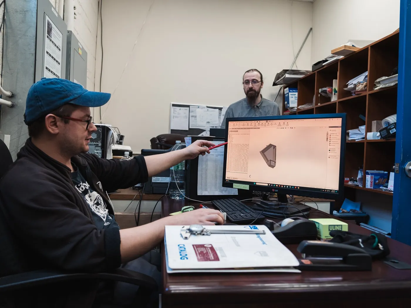 Engineer at a workstation pointing at a formed part in a 3D model
