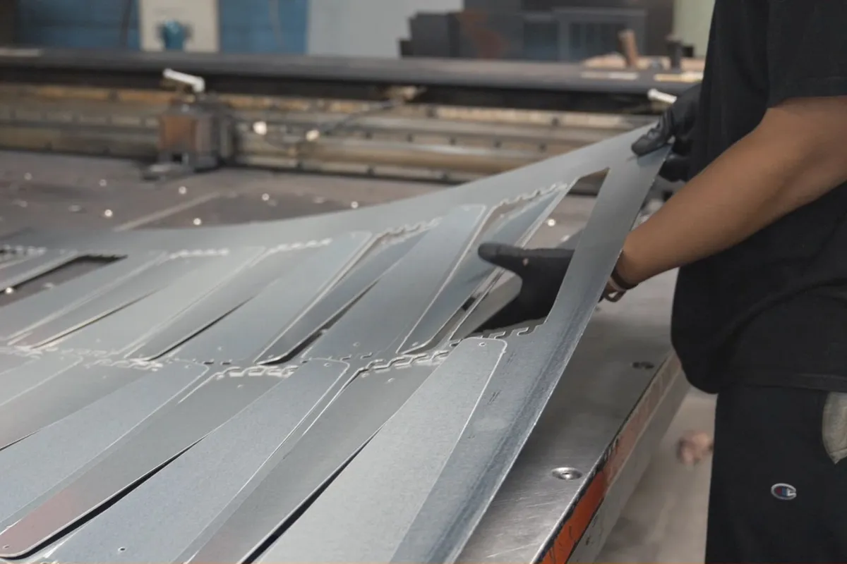 Operator lifting a formed steel strip off the brake