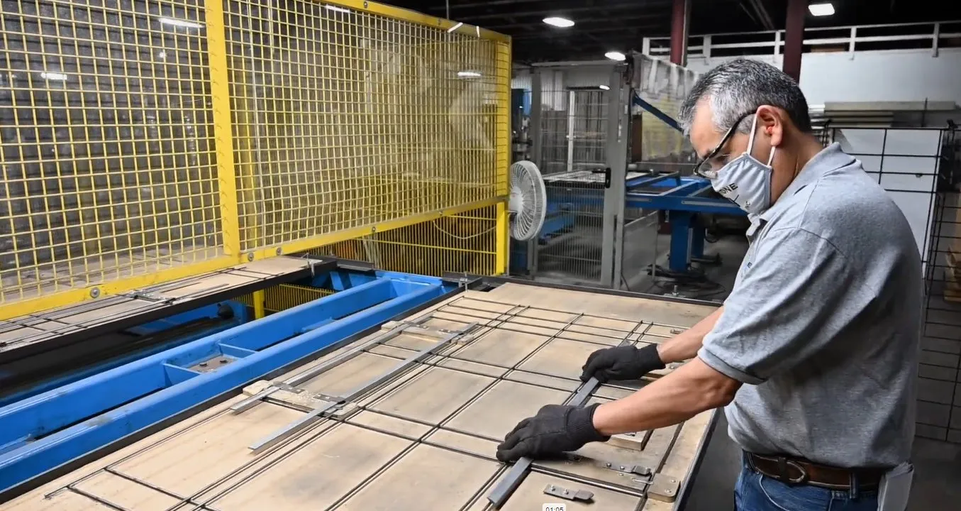 Operator welding a wire grid on a yellow fixture
