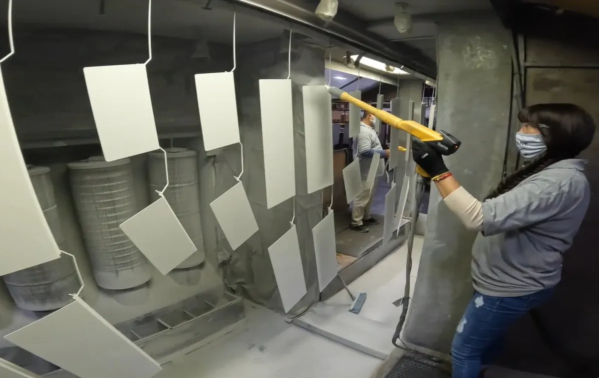 Operator spraying powder onto hung parts in the coating booth