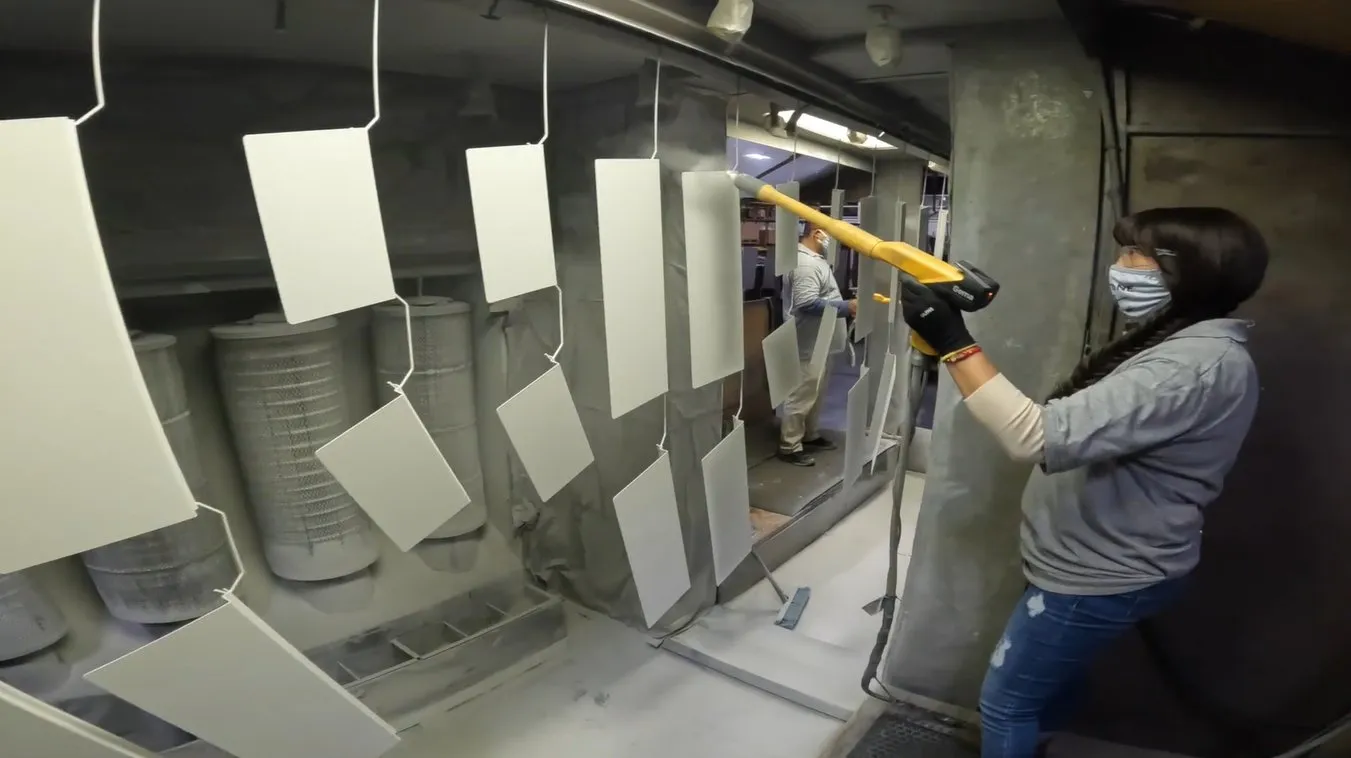 Operator spraying powder onto hung parts in the coating booth