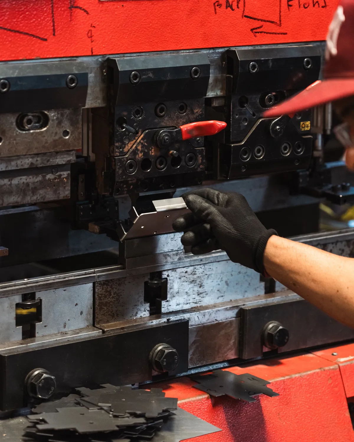 Gloved hands feeding a metal blank into a press brake