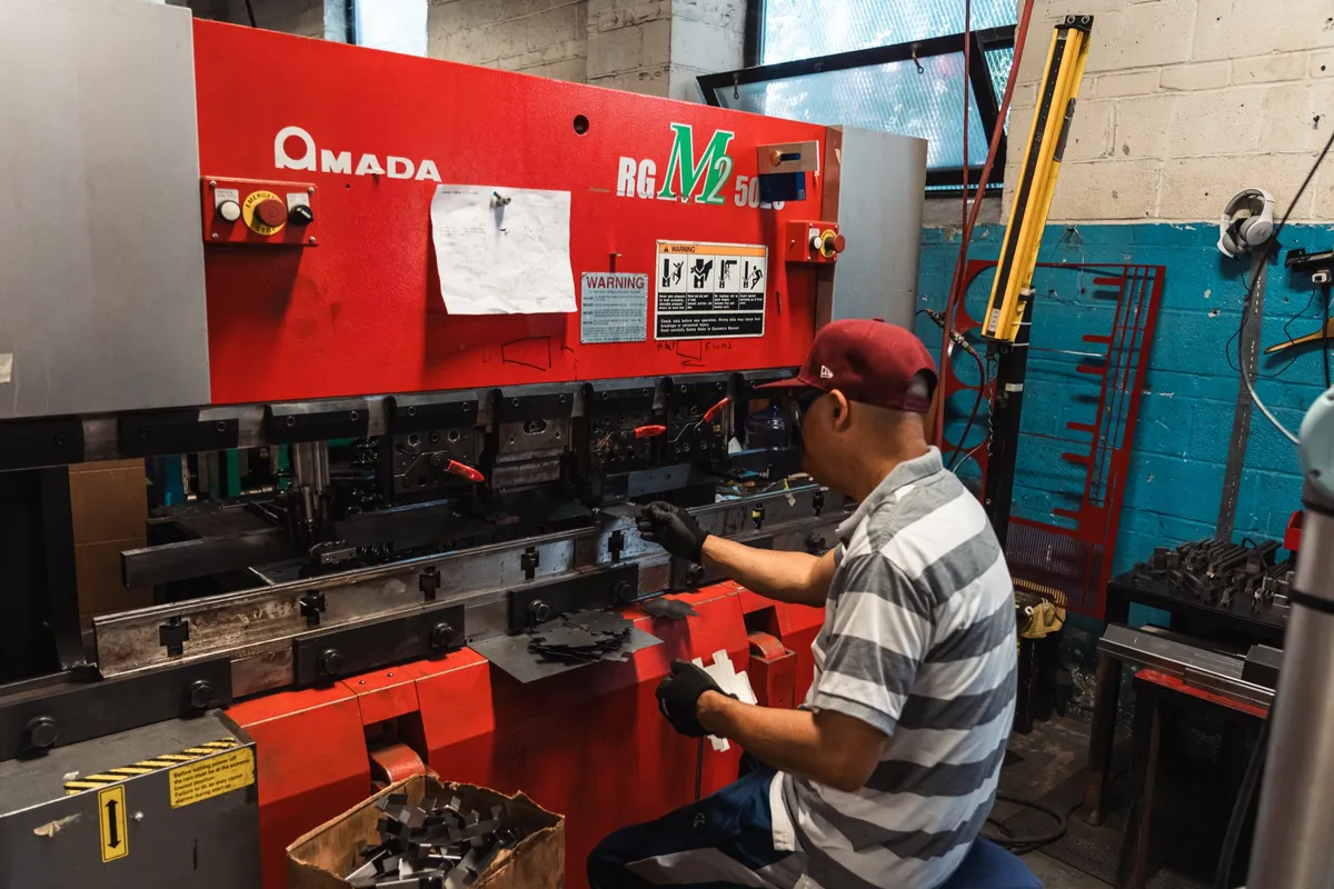 Operator at the controls of a red Amada press brake