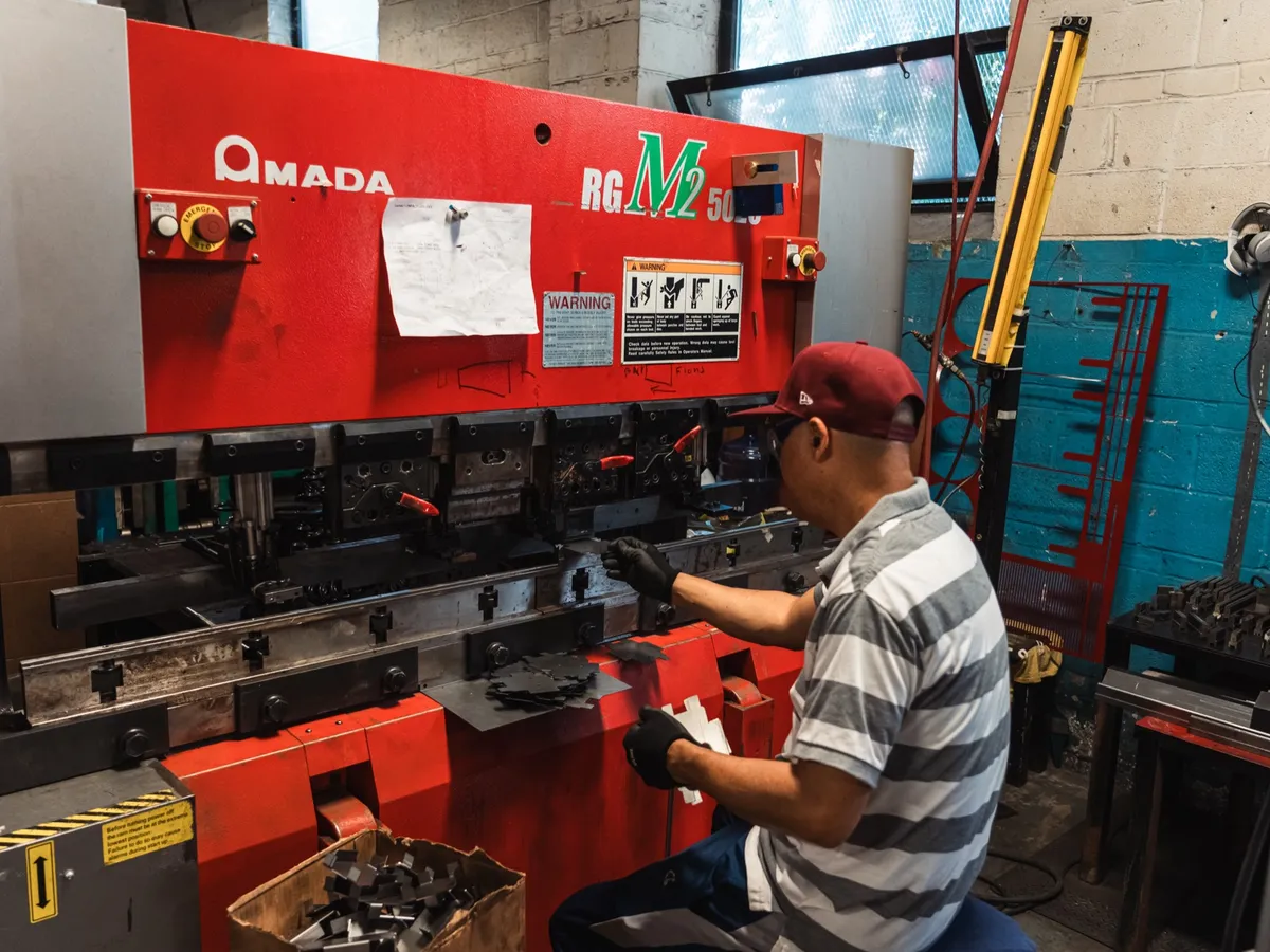 Operator at the controls of a red Amada press brake