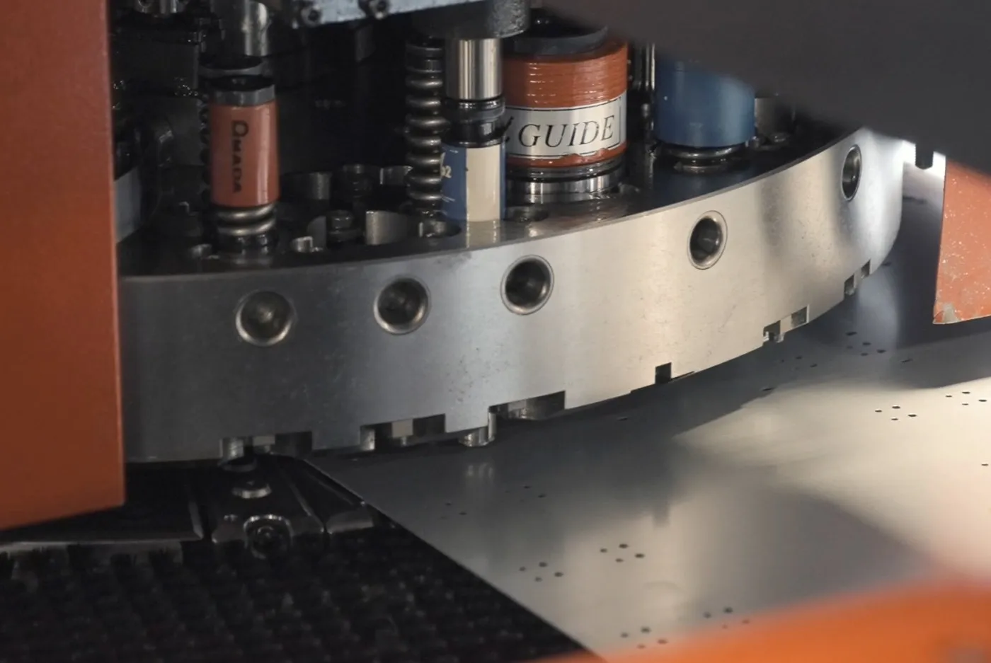 Close view of a turret punch tool station over a punched sheet