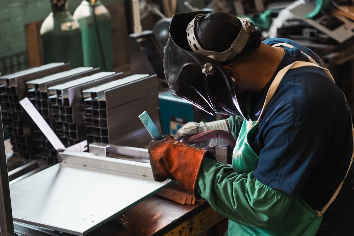 Welder working a white sheet metal panel assembly